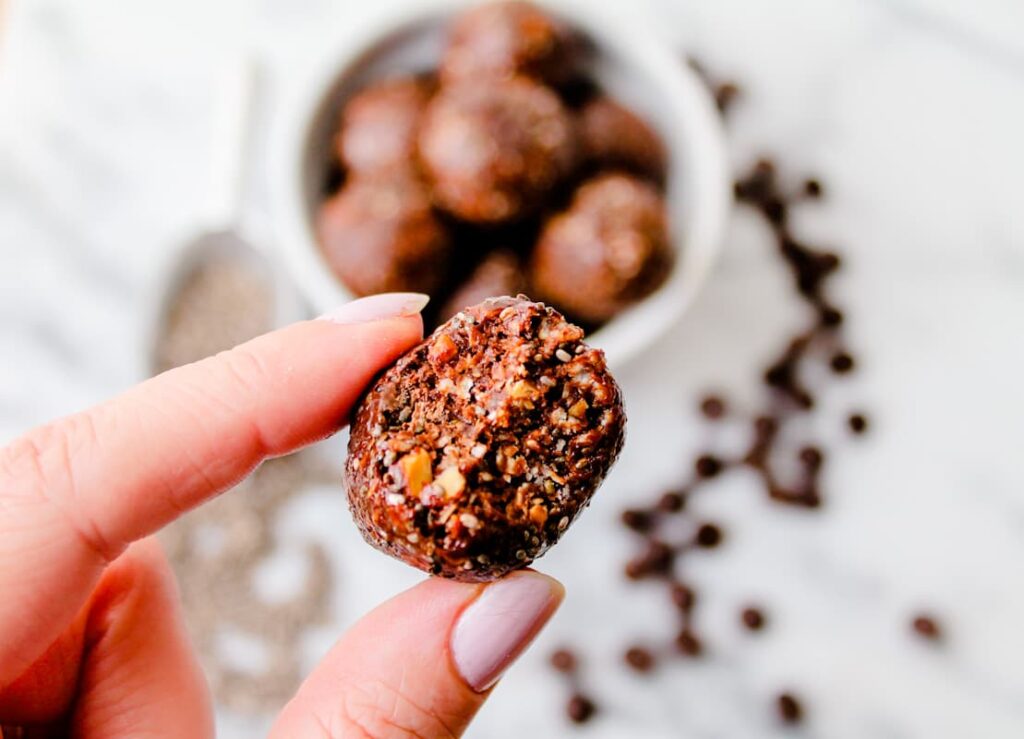 A hand holding a chocolate chia ball.