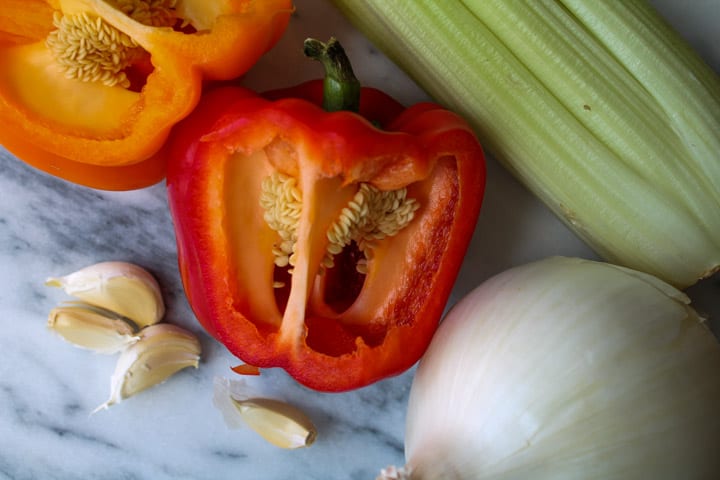 Cut bell peppers, onion and celery on a a marble chopping board