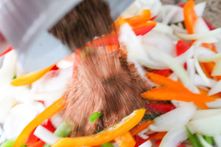 taco seasoning being poured over chopped veggies