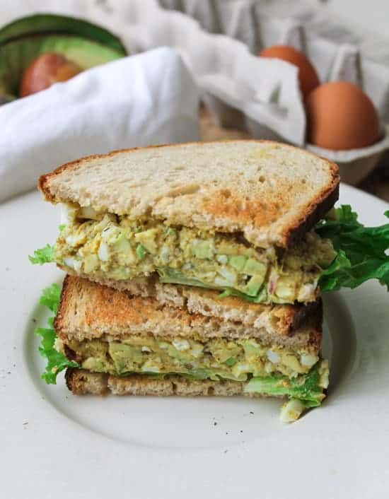 A curried egg salad sandwich on a plate.