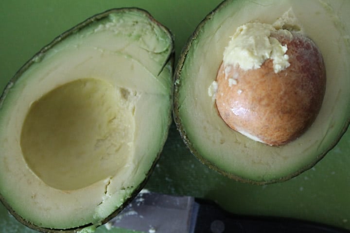 a fresh avocado sliced open on a cutting board
