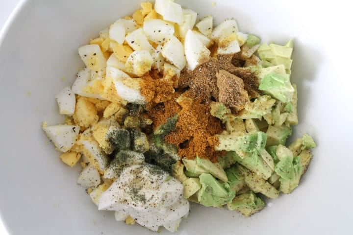 Chopped eggs, fresh avocado and spices in a bowl