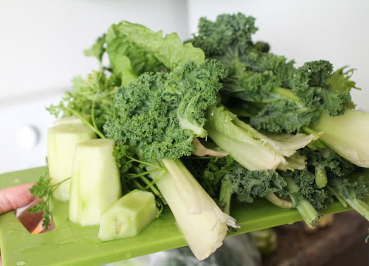 a board of kale leaves, celery, and cucumber