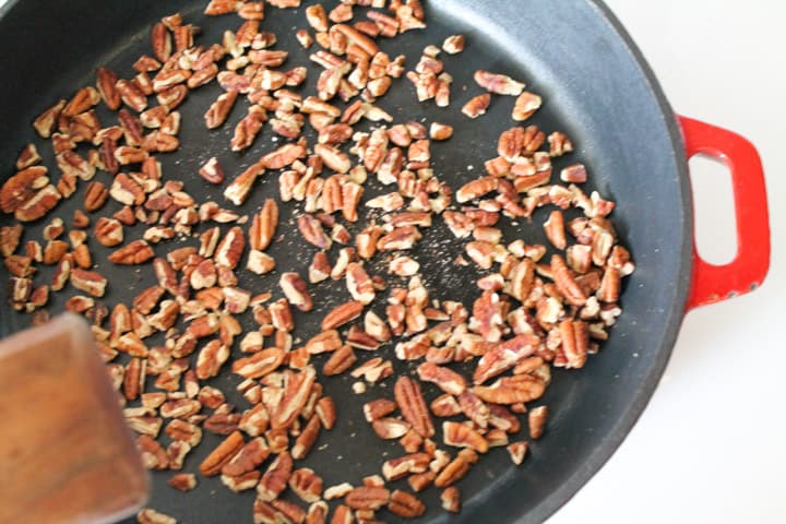 Nuts toasting on a stove top in a cast iron pan