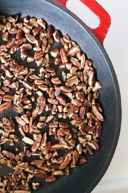 Pecans toasting in a large cast iron skillet