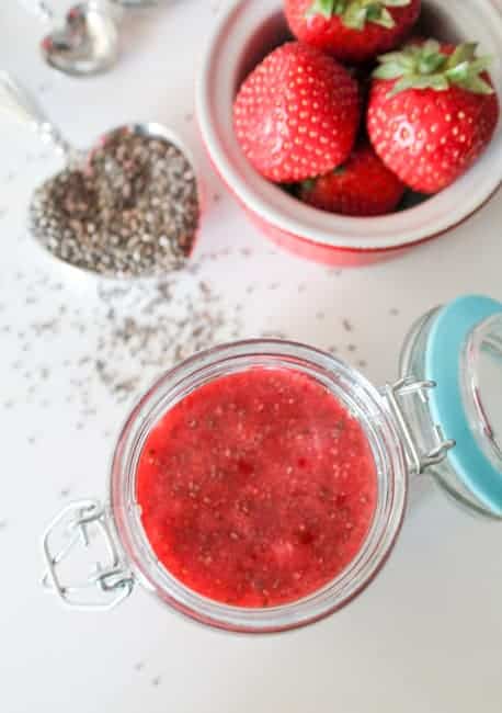 Chia Seed Jam in a jar with a bowl of strawberries in the background