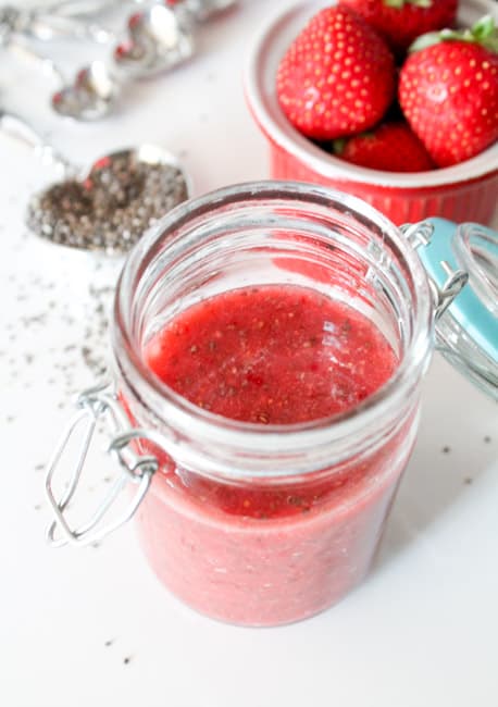 Chia Seed Jam in a jar with chia seeds and fresh berries in the background