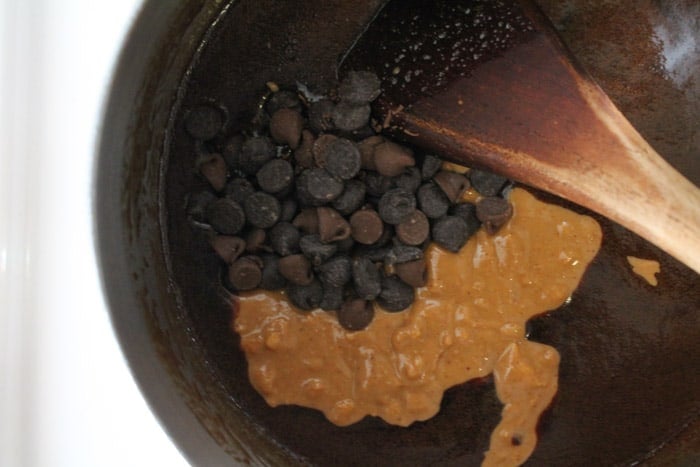 Peanut butter and chocolate chips being stirred in a saucepan