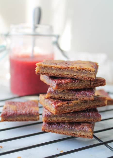 Peanut Butter & Jelly Cookie Bars on a wire rack with a jar in chia jam in the background