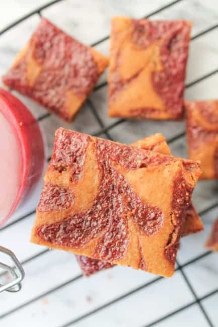 Peanut Butter & Jelly Cookie Bars on a wire baking rack with a jar of chia jam in the background