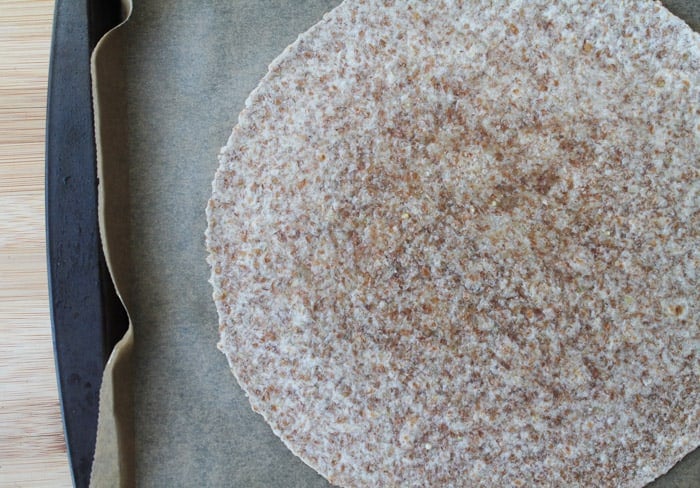 a 10 inch tortilla on a parchment lined baking sheet