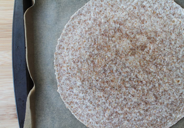 a 10 inch tortilla on a parchment lined baking sheet