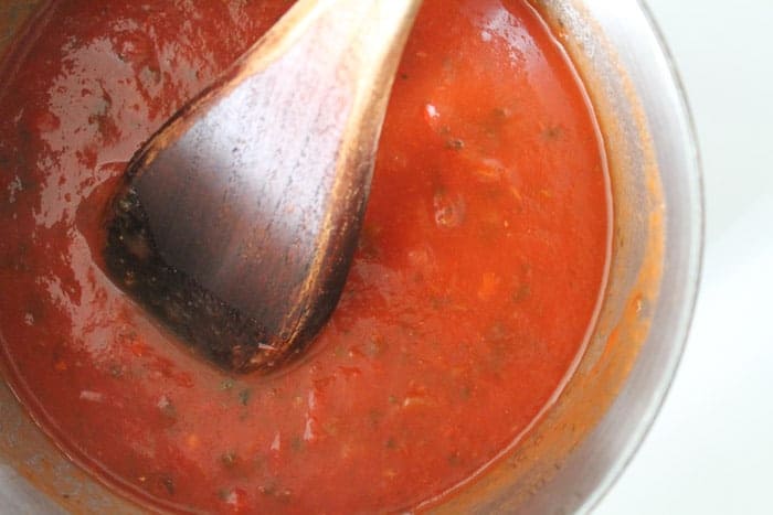Tomato sauce being stirred in a saucepan