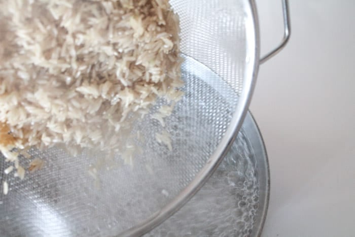 Rice is a sieve being dumped into a pot of boiling water