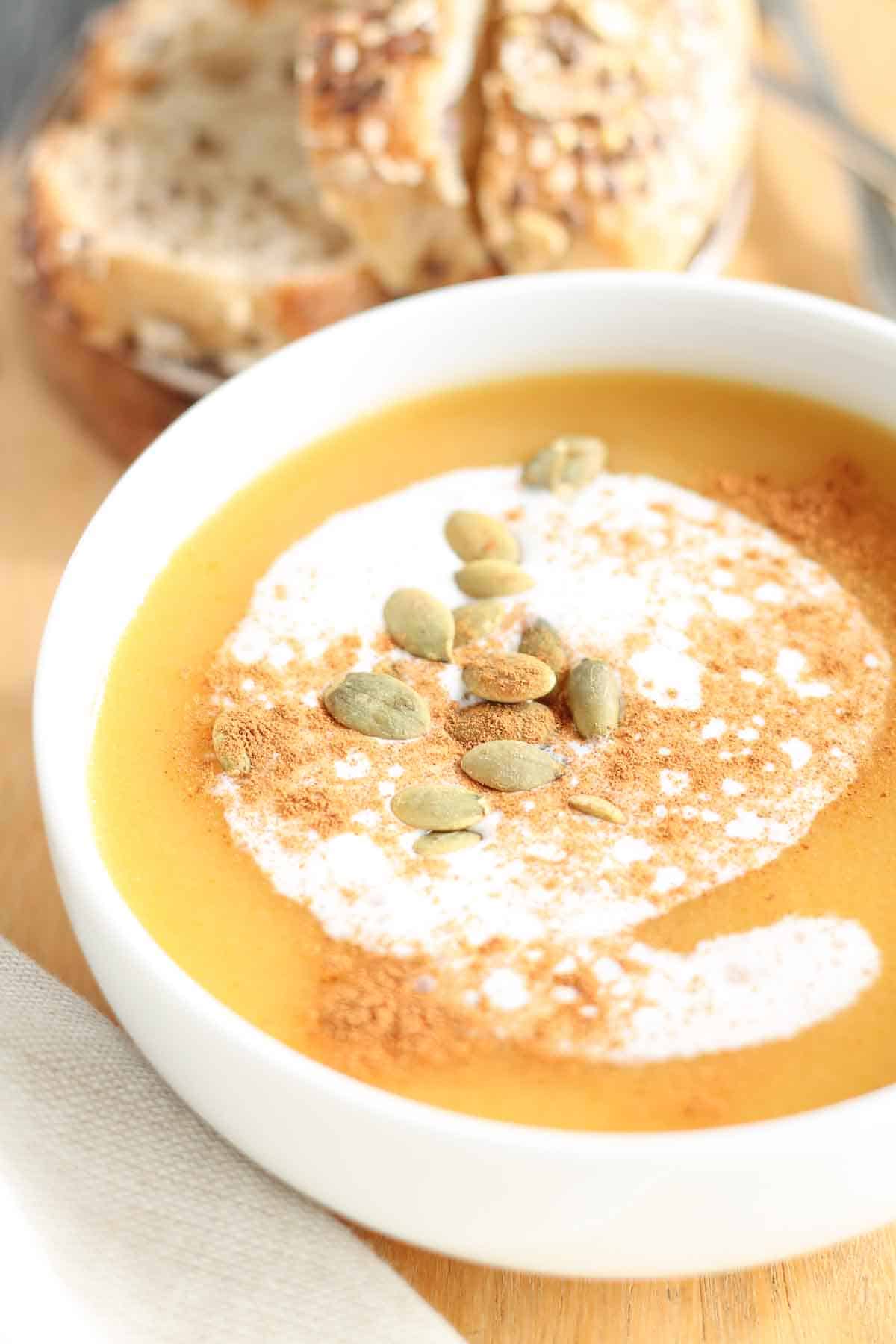bowl of butternut squash soup garnished with pumpkin seeds and a sprinkle of cinnamon
