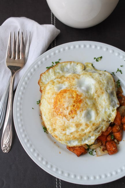 Sweet Potato Hash with Eggs on a plate with a mug in the background