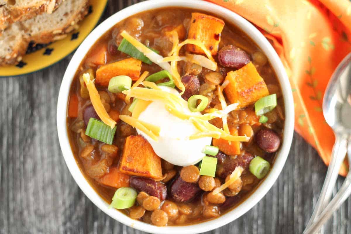 vegetarian lentil chili with roasted butternut squash in a bowl garnished with green onions