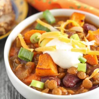 vegetarian lentil chili with roasted butternut squash in a bowl garnished with green onions