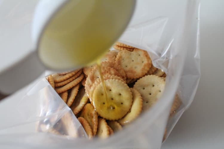 Crackers in a ziploc bag with olive oil being poured overtop