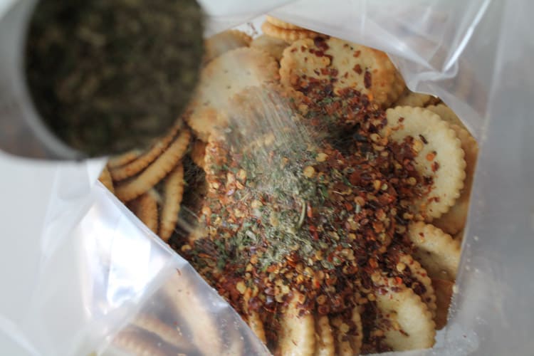 Spices being poured over crackers in a ziploc bag