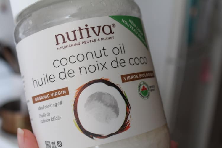 a hand holding a jar of coconut oil