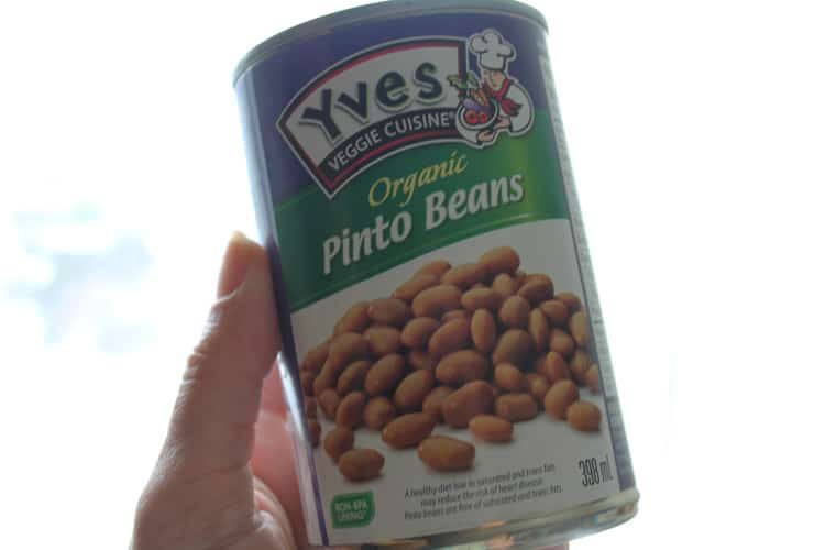 a hand holding a can of pinto beans