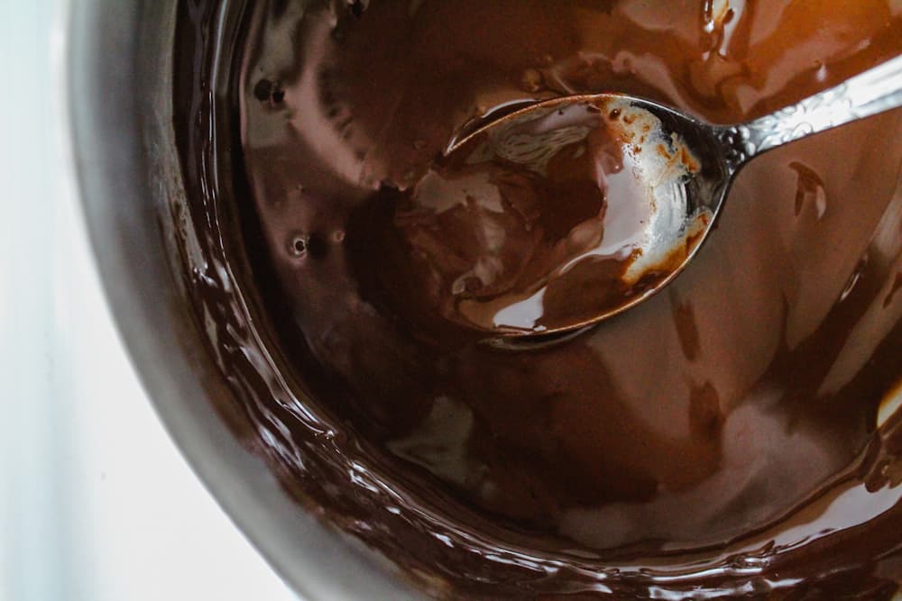 a spoon stirring melted chocolate in a saucepan.