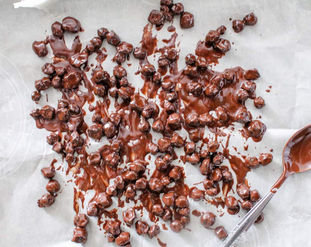 a cluster of chocolate covered blueberries on parchment paper.