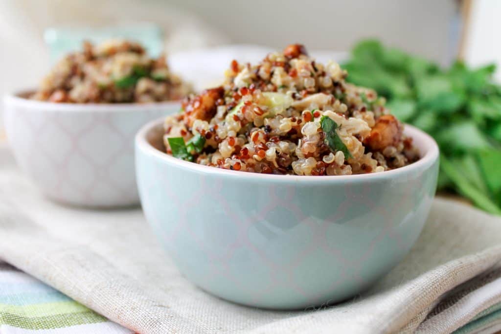 Lemon Chicken Quinoa Salad in a bowl with fresh lemons in the background