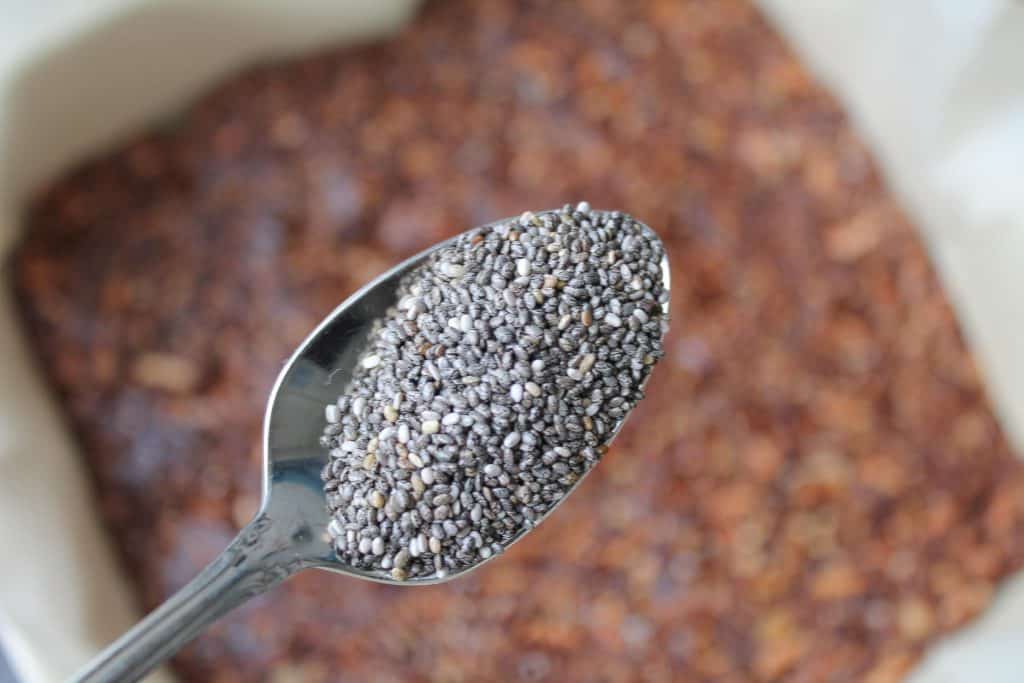 spoon full of chia seeds about to be sprinkled over chocolate mixture