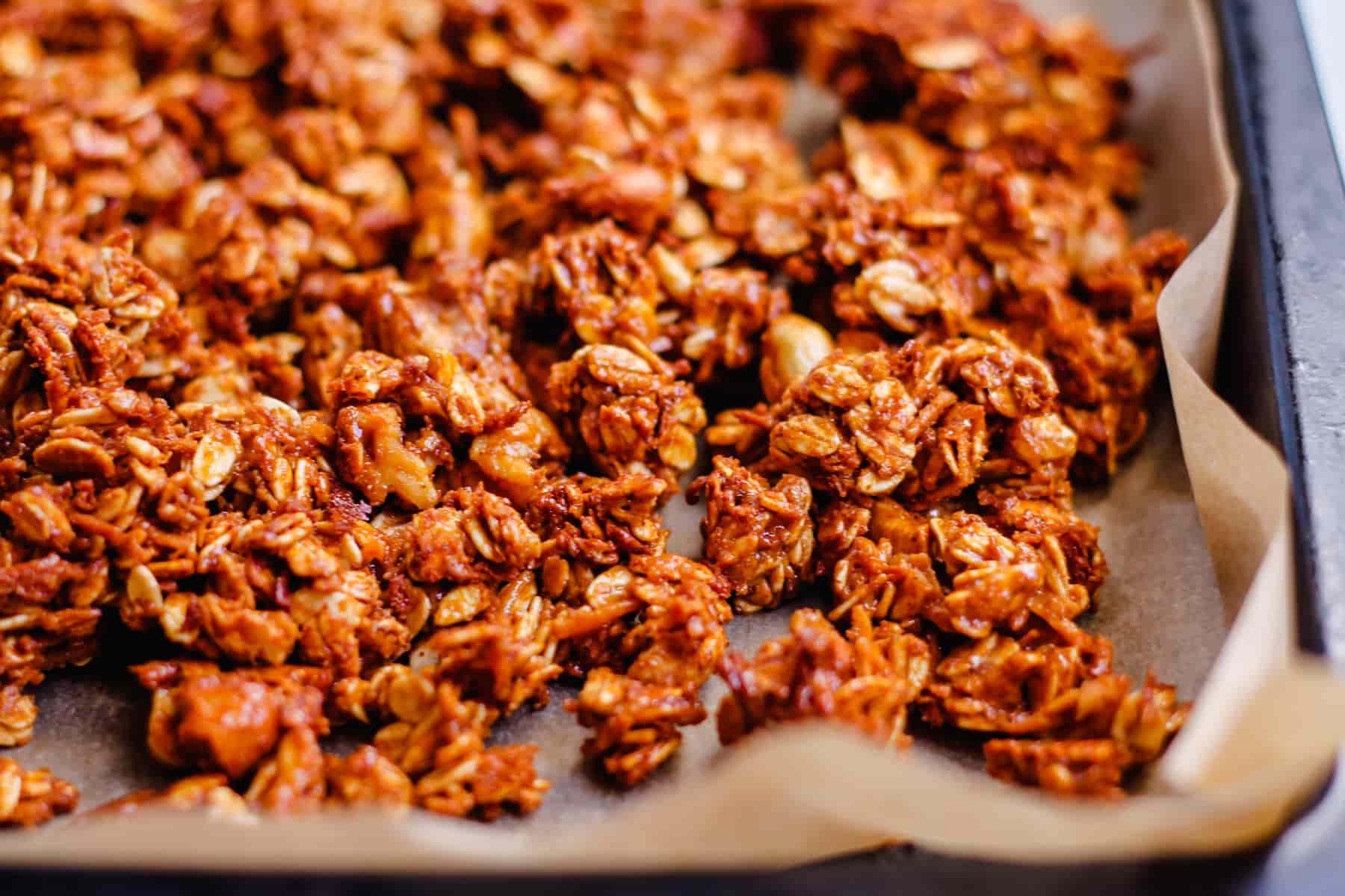 clusters of honey nut granola cooling in a pan.