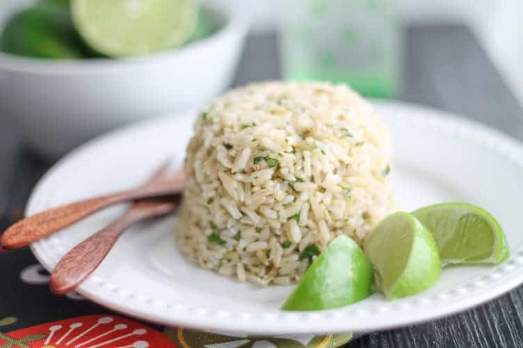 Cilantro Brown Rice on a white plate with wedges of fresh lime