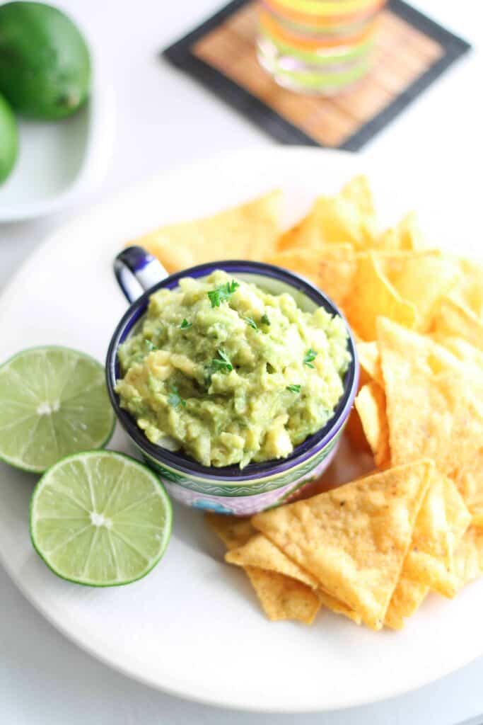 Easy Guacamole on a plate with chips and fresh limes