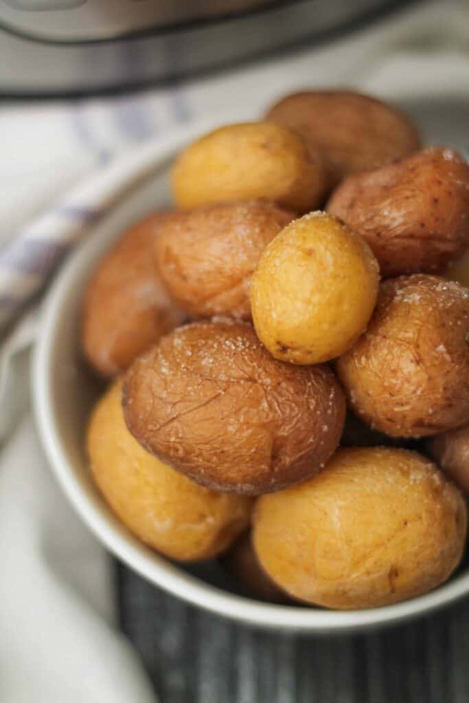 Instant Pot Salted Potatoes in a bowl on a wooden surface with a soft white napkin in the background.