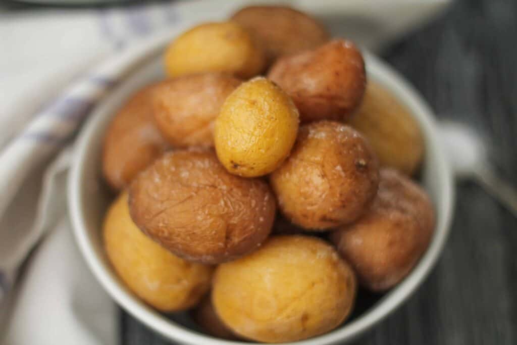 Instant Pot Salted Potatoes in a bowl on a wooden surface with a soft white napkin in the background.