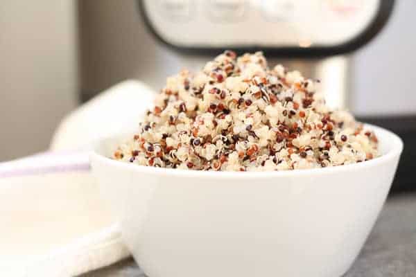 Perfectly cooked quinoa in a white bowl with an Instant Pot in the background