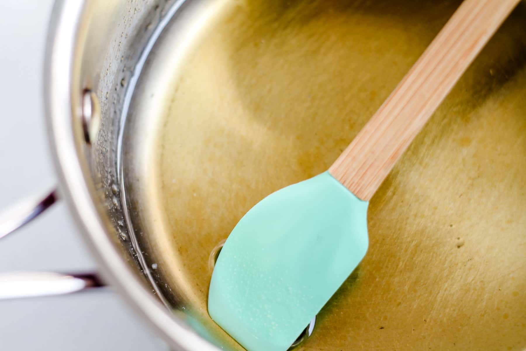 coconut oil and maple syrup being stirred in a saucepan.