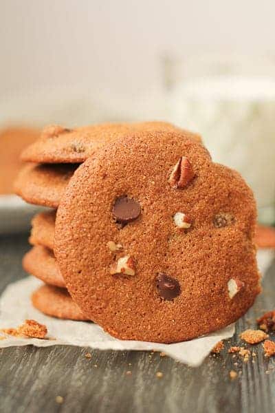 Cookies on a dark wood surface with a glass of milk in the background