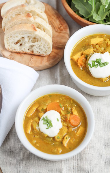 Brown Rice Mulligatawny Soup in a white bowl topped with a dollop of sour cream