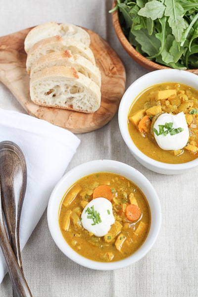 Brown Rice Mulligatawny Soup in a white bowl topped with a dollop of sour cream