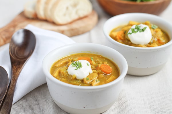 Brown Rice Mulligatawny Soup in a white bowl topped with a dollop of sour cream