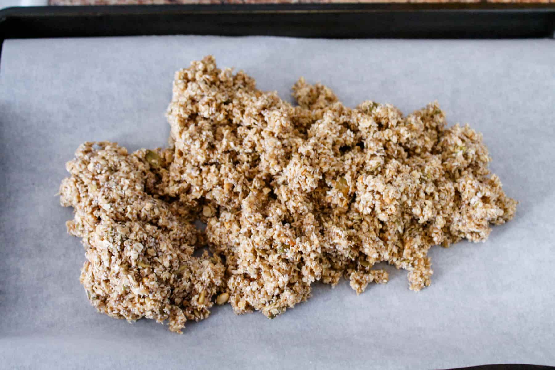 a pile of the oat mixture on a parchment lined baking sheet.
