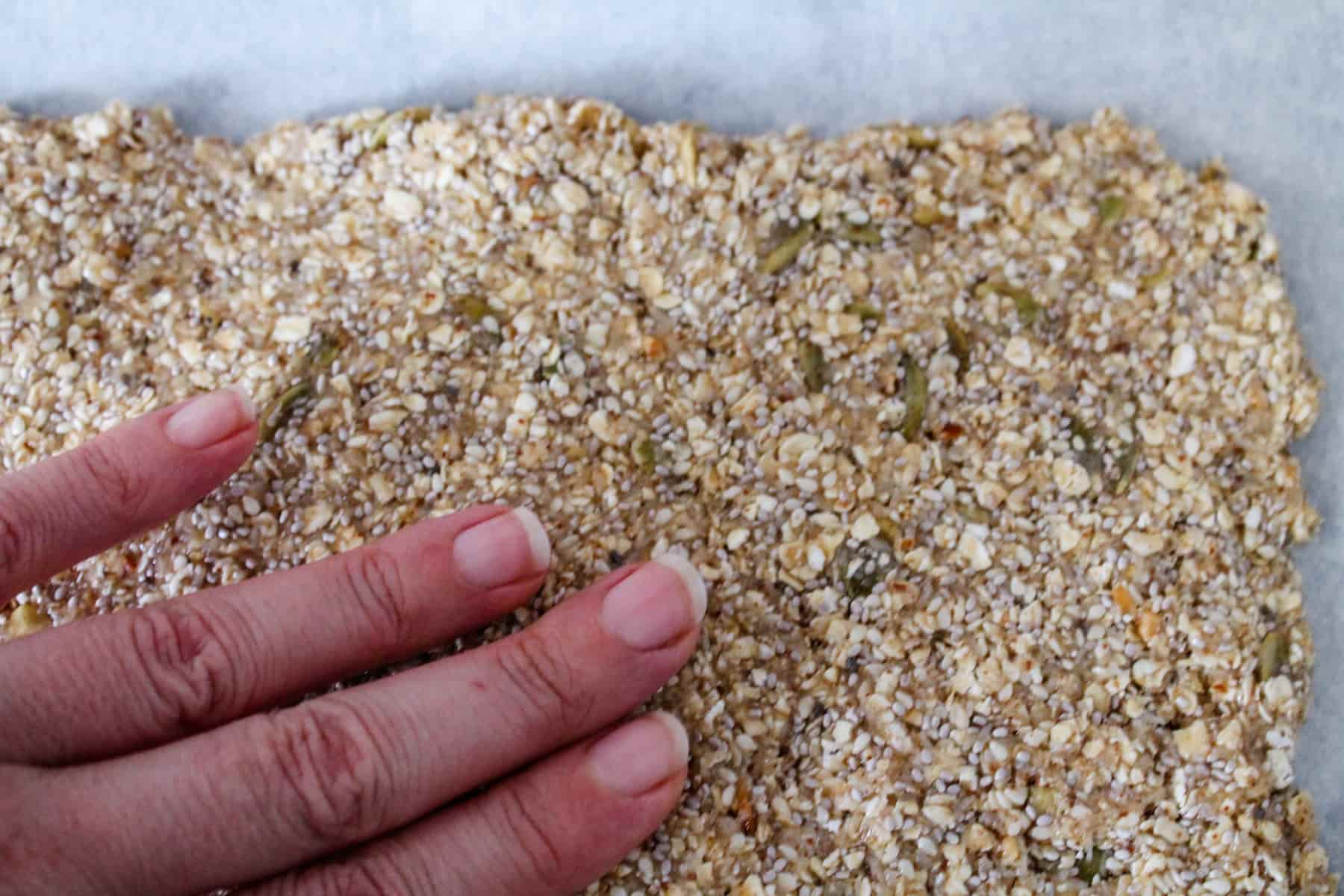 a hand flattening the oat mixture.