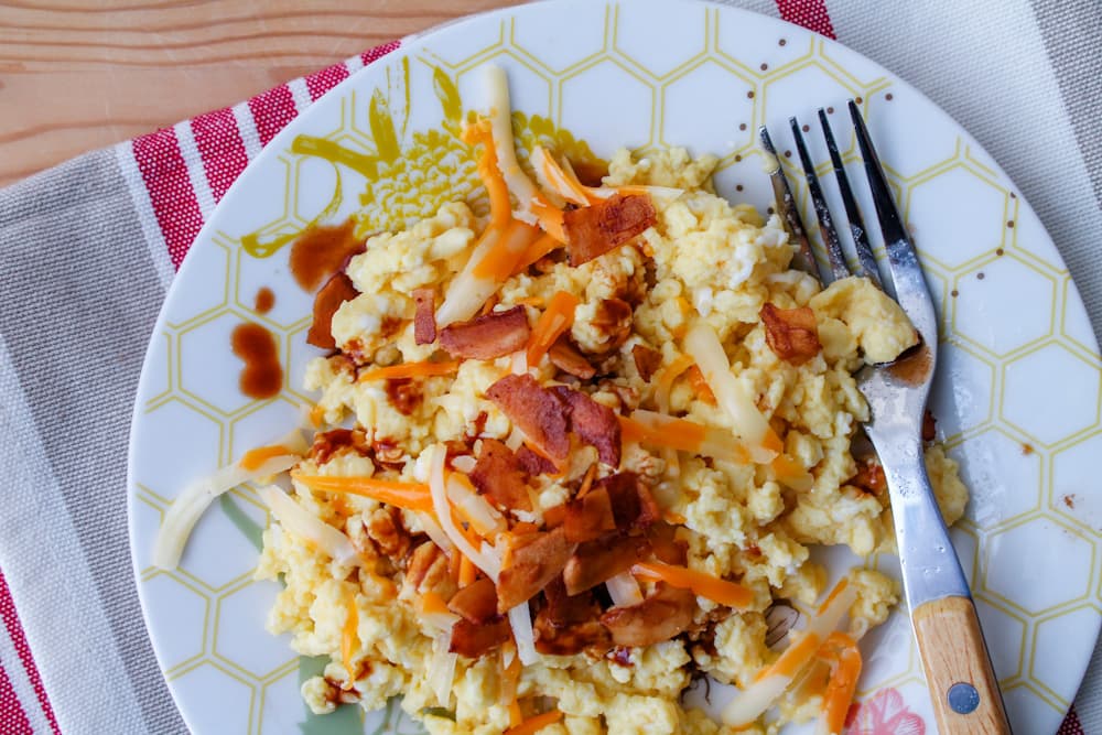 a plate of scrambled eggs with vegan bacon.