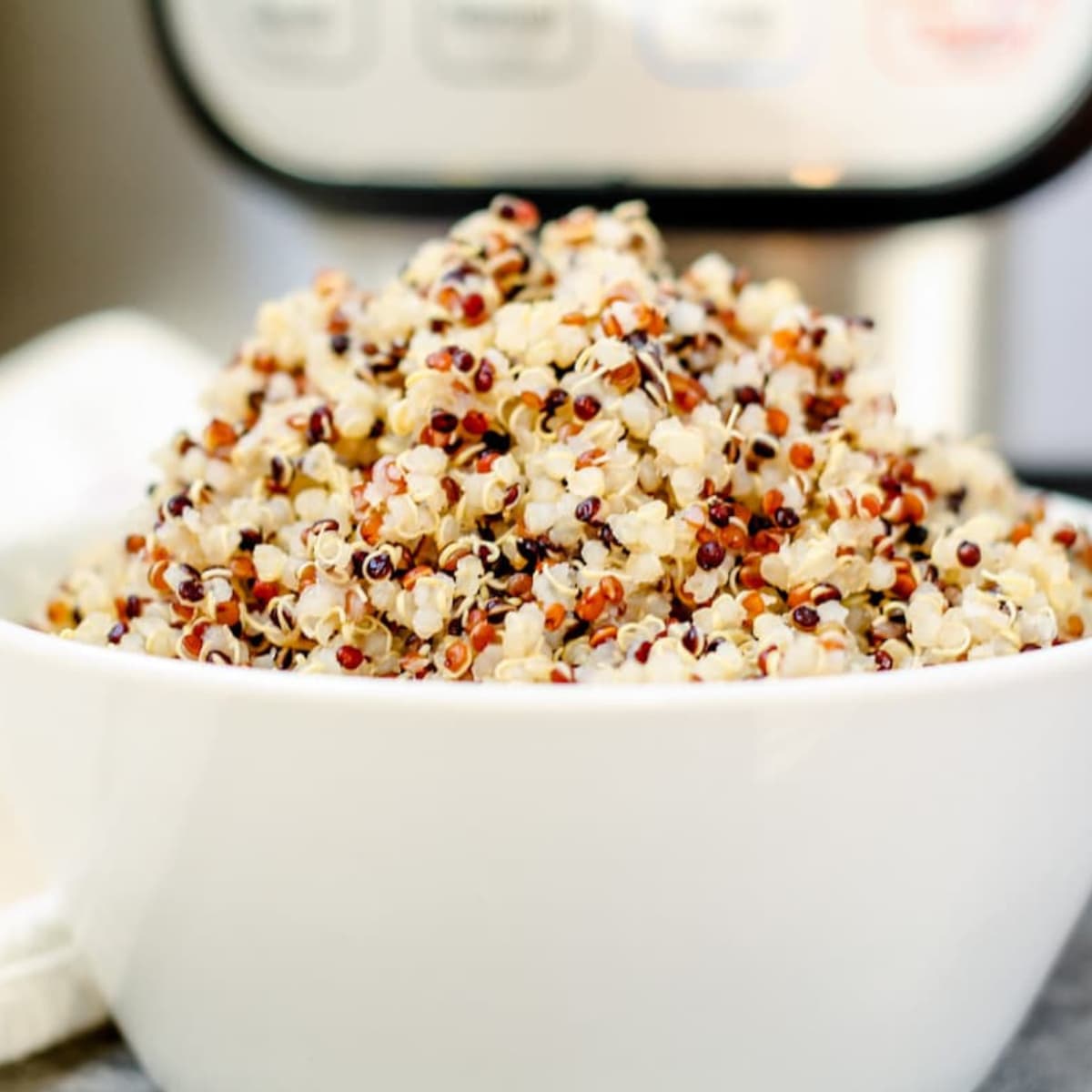 A bowl of quinoa in front of an Instant Pot.