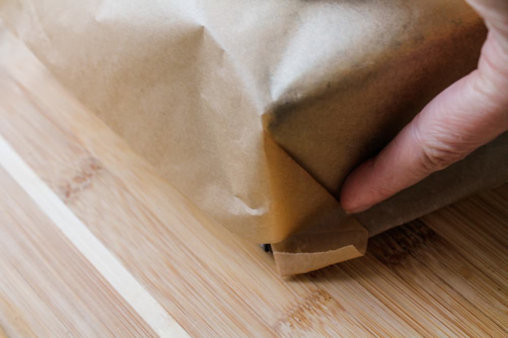 parchment paper being folded over a loaf pan.
