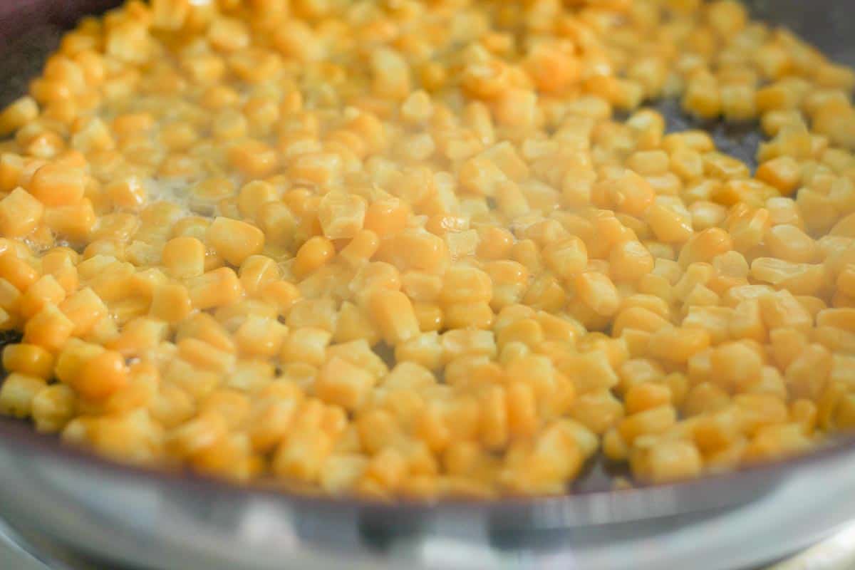 corn simmering in a pan with butter sauce bubbling