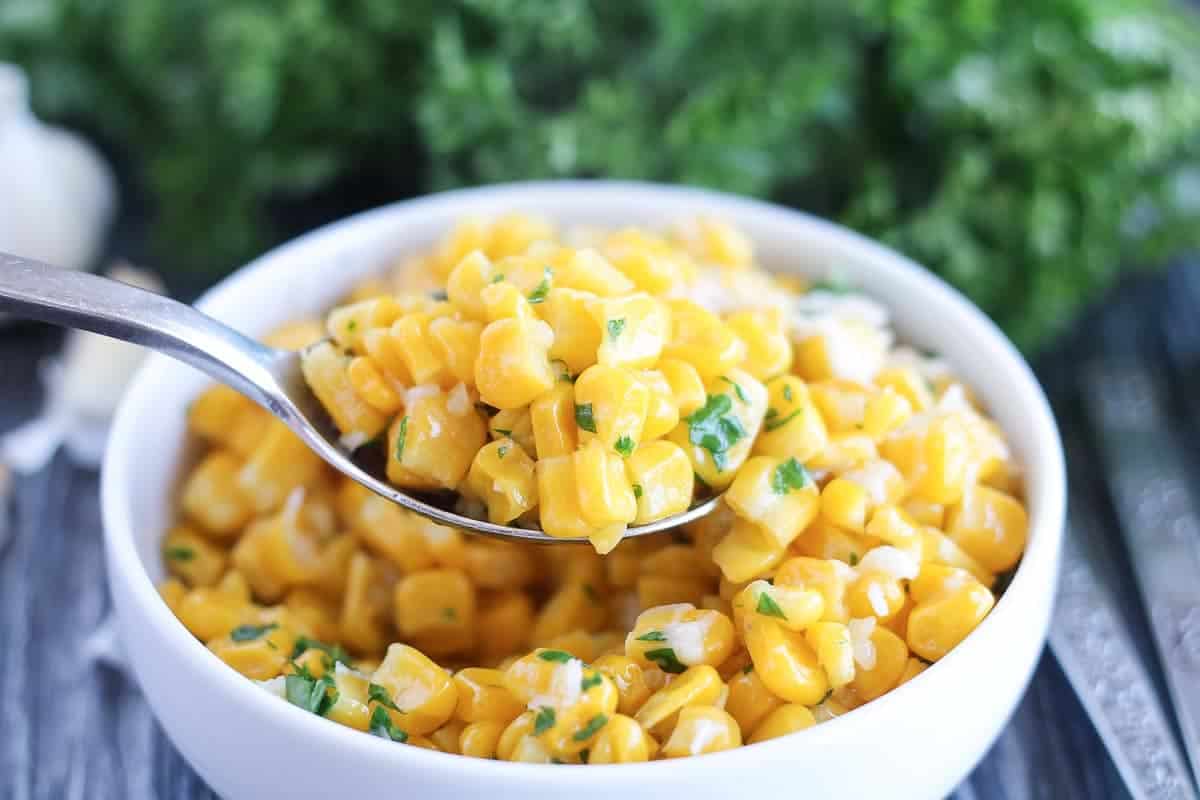 a bowl of garlic butter fried cor with fresh parsel and parmesan sprinkled on top 