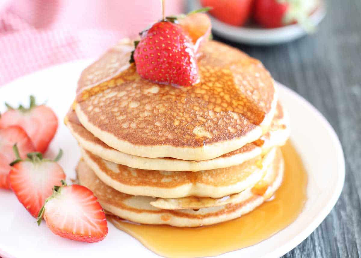 quinoa flour pancakes drizzled maple syrup and garished with fresh strawberries