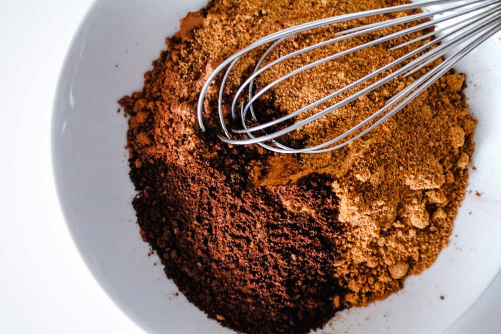 a bowl of cocoa, coconut sugar, cinnamon and instant coffee being whisked together.